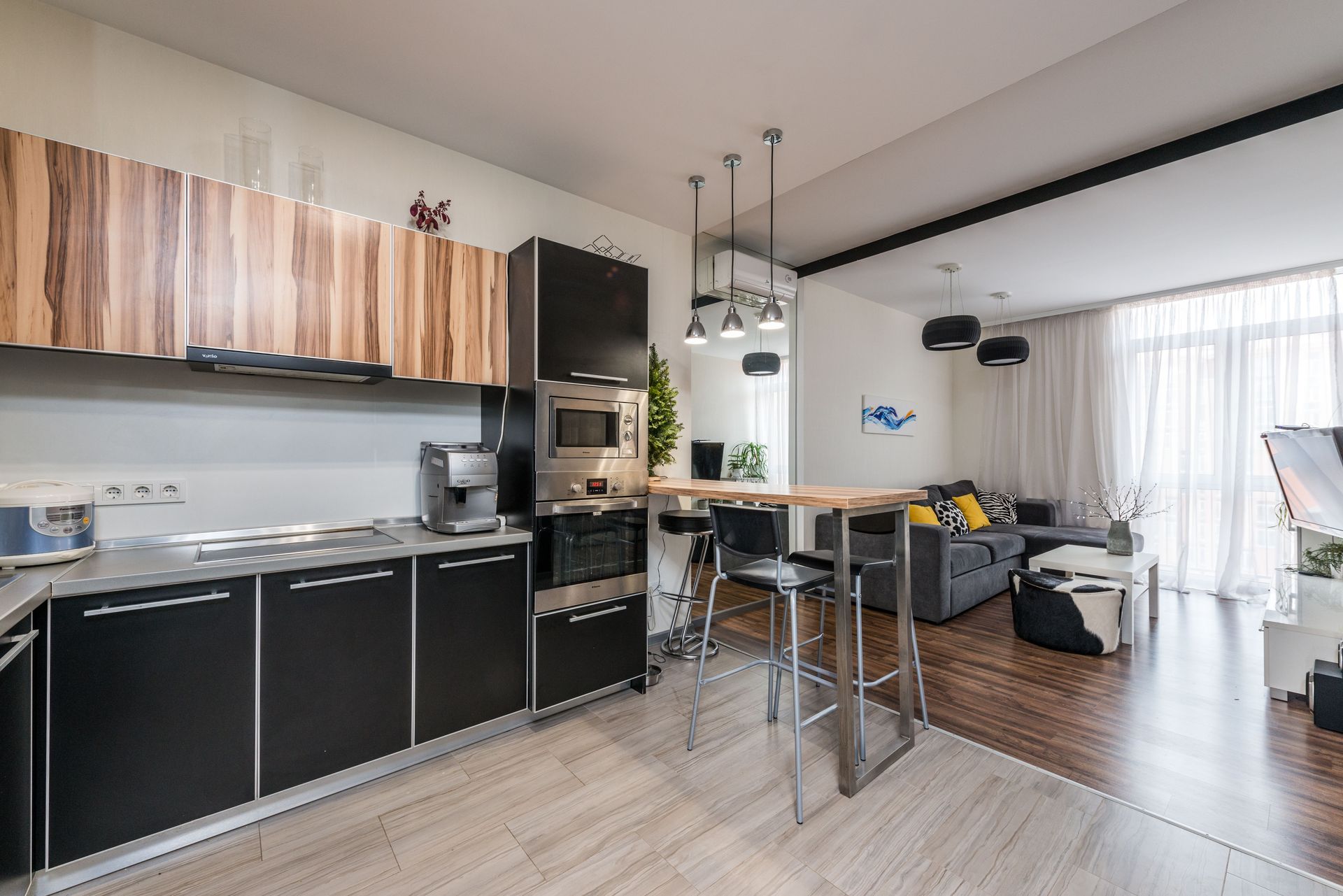 Interior or modern studio apartment with black furniture in kitchen zone and comfortable sofa with coffee table in living room